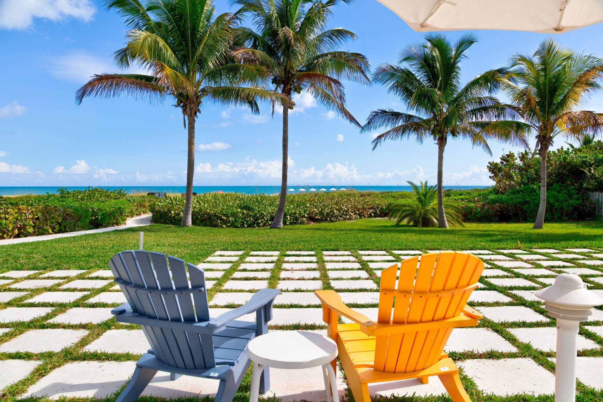 Blue and orange lawn chairs with palm trees and beach in the background